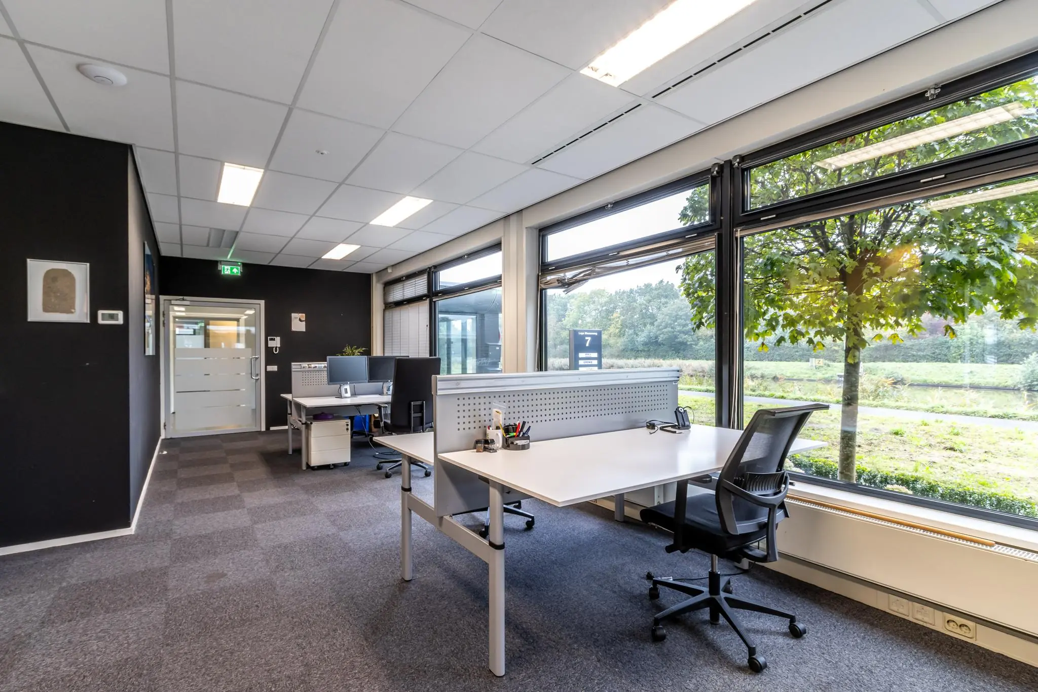 Modern kantoorinterieur aan de Lage Biezenweg met werkplekken en uitzicht op groen buitengebied.